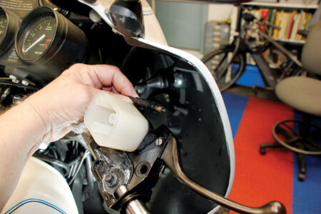 A hand unscrewing the brake switch.